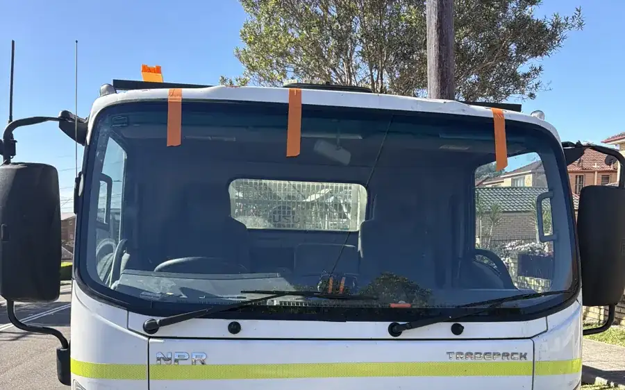 Isuzu NPR truck with a taped windscreen ready for mobile truck windscreen replacement in Sydney